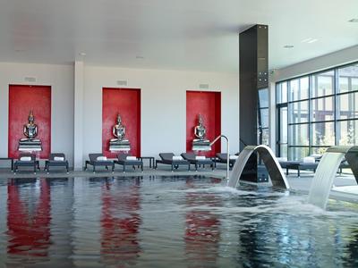 Moderner Innenpool mit Wasserfontänen, roten Wänden und Dekorationen in schwarzer Statue.