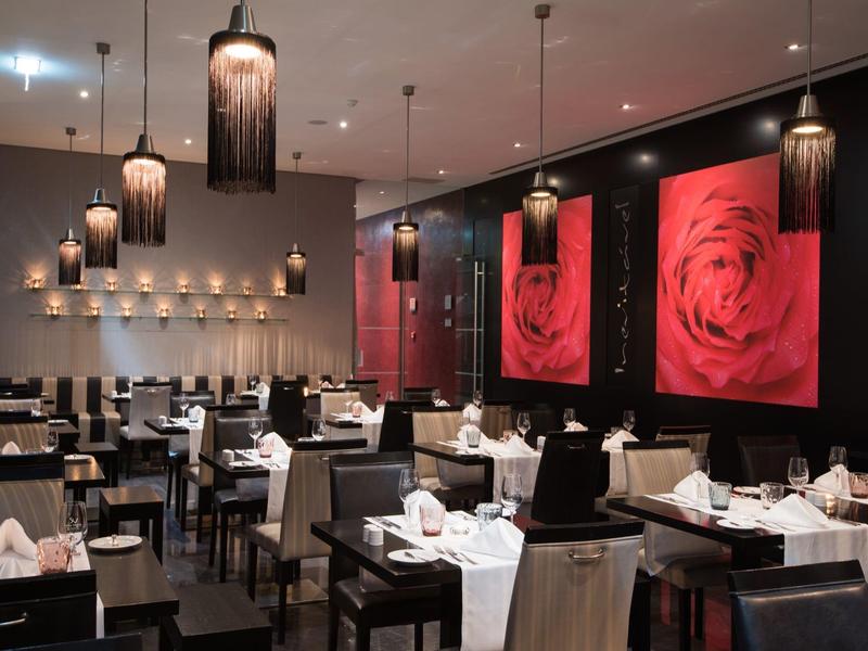 Modernes Restaurant mit schwarzem und weißem Mobiliar und großen roten Rosenbildern an der Wand.