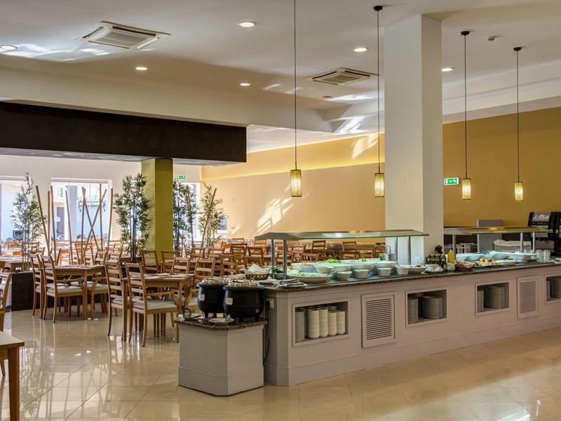 Moderne Hotelcafeteria mit Buffetbereich und zahlreichen Holztischen und -stühlen.