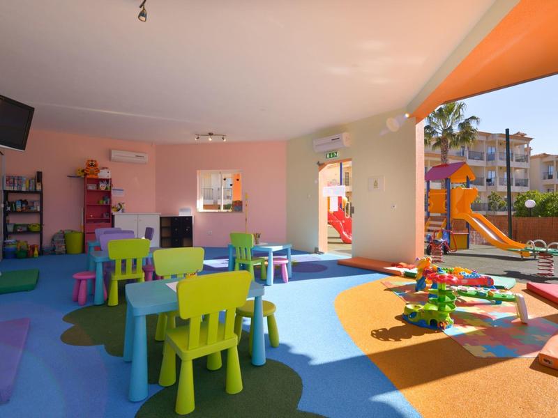 Bunter Kinderspielraum mit bunten Tischen, Stühlen und Spielgeräten in Hotelumgebung