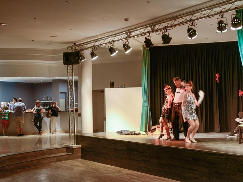 Mehrere Personen führen eine Tanzaufführung auf einer Bühne in einem Veranstaltungsraum auf.