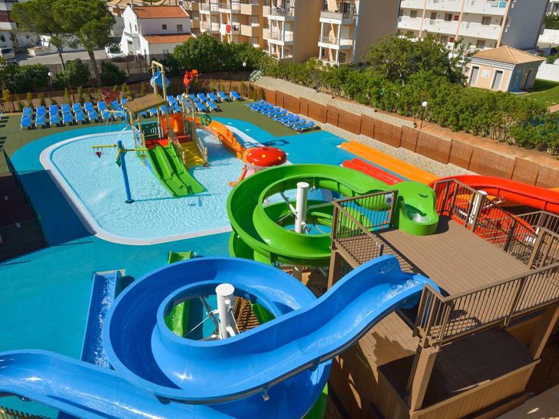 Wasserpark mit bunten Wasserrutschen und Schwimmbecken in einer Urlaubsanlage.