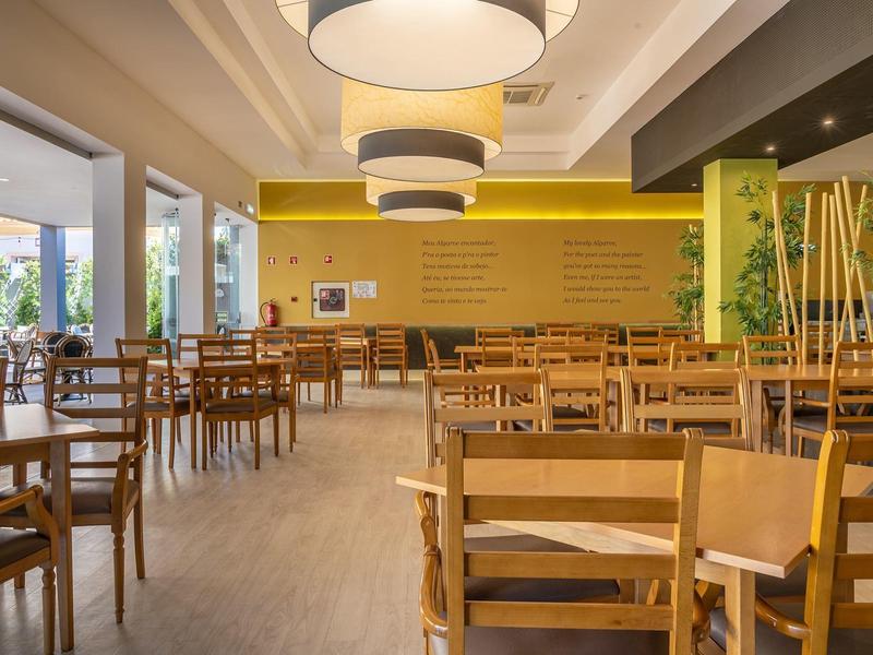 Helles, modernes Restaurant mit Holzmöbeln und gelben Wänden.