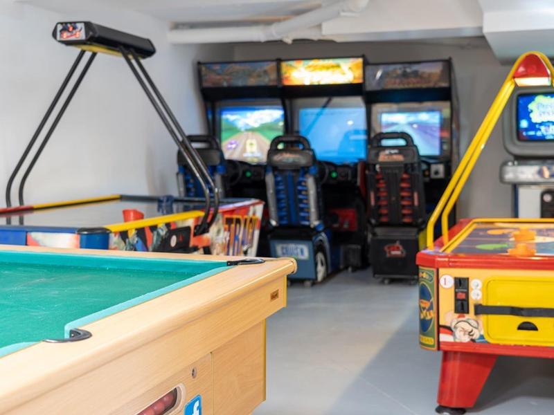 Ein Spielzimmer mit einem Airhockey-Tisch, einem Billardtisch und mehreren Rennspiel-Automaten.
