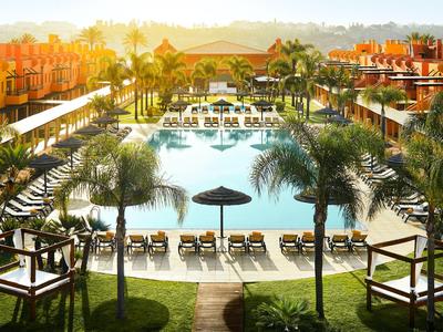 Luxuriöser Hotelpool mit Liegestühlen und Palmen bei Sonnenuntergang.