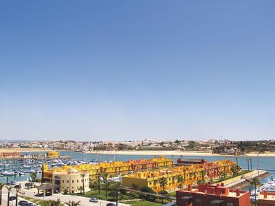 Hafen mit Booten, bunten Häusern, grünem Rasen und klarem blauem Himmel im Hintergrund.