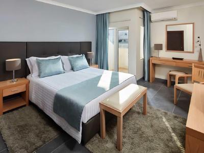 Gemütliches Schlafzimmer mit großem Bett, Holzmöbeln und Teppich in neutralen Farbtönen.