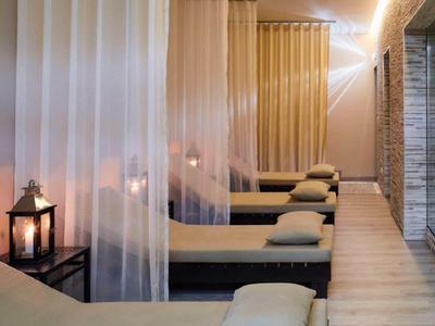 Eleganter Spa-Ruheraum mit bequemen Liegen, transparenten Vorhängen und warmem Licht.