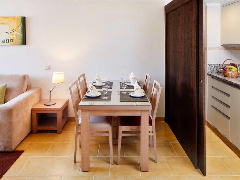 Moderner Essbereich mit Holztisch, sechs Stühlen, angrenzendem Sofa und offener Küche.