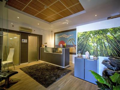 Moderner Empfangsbereich mit Holzdecke, großem Wandbild und grünen Pflanzen, heller Beleuchtung.