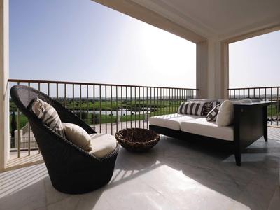 Moderne Terrasse mit Korbsessel, Sofa und Blick auf grünes Gelände bei Tageslicht.