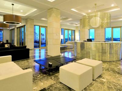 Großer, moderner Wohnraum mit weißem Mobiliar, Marmorboden und großen Fenstern mit Blick nach außen.