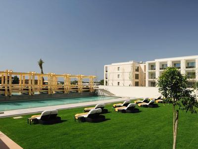 Moderner Pool mit Liegestühlen, Grünfläche und Gebäuden unter klarem Himmel.