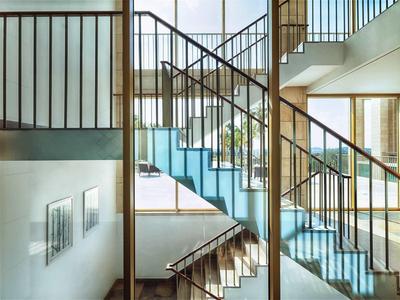 Moderne Treppe mit blauem Teppich und schwarzem Metallgeländer in hellem Innenraum.