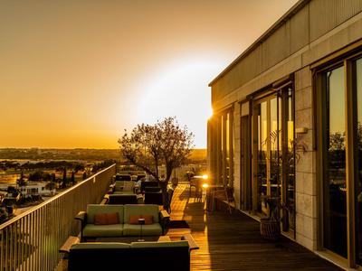 Hotelterras met comfortabele zitplaatsen, zonsondergang en een uitgestrekt uitzicht over het landschap.