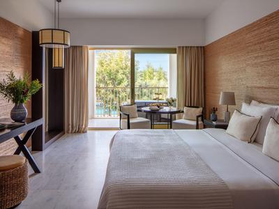 Moderne hotelkamer met tweepersoonsbed, bureau en balkon met uitzicht op bomen.