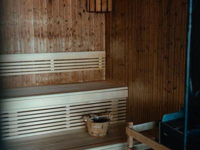 Hout sauna met tweedelige bank, houten emmer en warm plafondlicht.