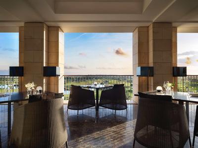 Moderner Essbereich mit dunklen Stühlen, Tischen und offenem Blick auf eine Aussicht unter blauem Himmel.