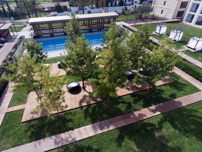 Moderner Garten mit Bäumen, Swimmingpool, Sitzbereichen und umlaufenden Gehwegen in Wohnanlage.