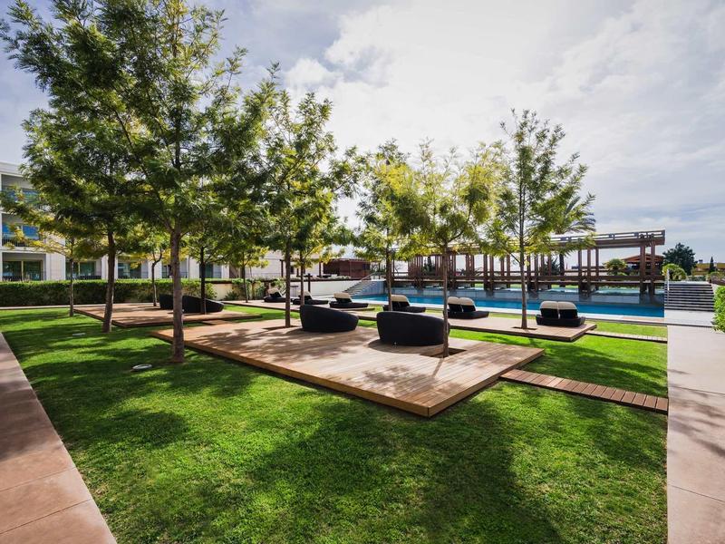 Moderner Außenbereich mit grünen Bäumen, Holzdeck, Pool und mehreren schwarzen Sitzmöbeln.