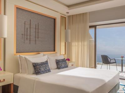 Helles Hotelzimmer mit Doppelbett, modernem Dekor und Balkon mit Meerblick.