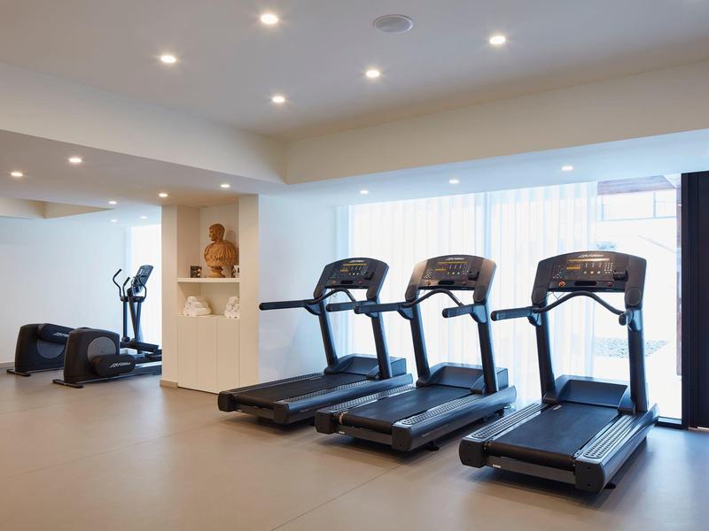 Moderne Fitnessraum mit drei Laufbändern, Cardio-Geräten und heller Beleuchtung.