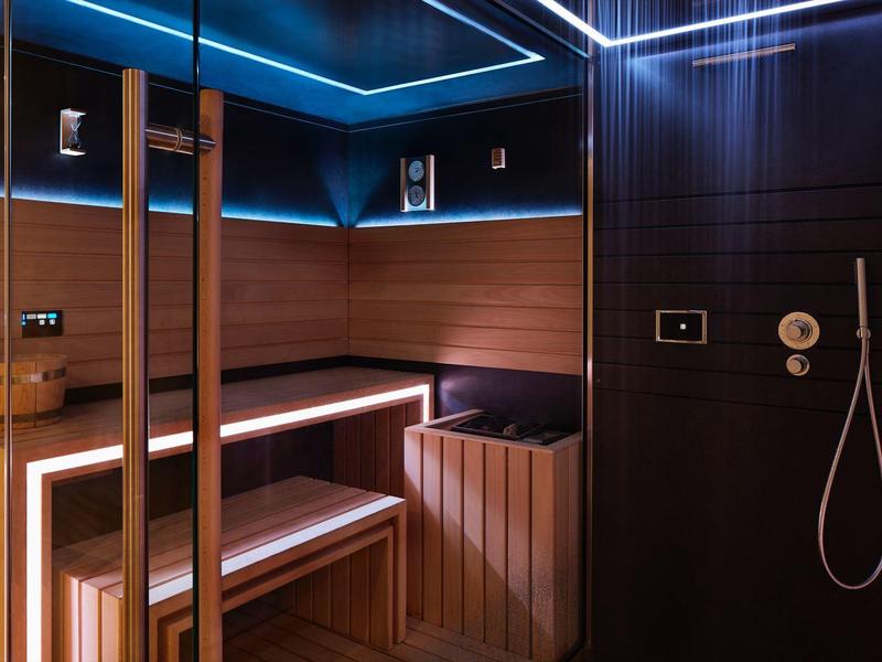Moderne Sauna mit Holzbänken und indirekter blauer Beleuchtung, entspannte Atmosphäre.