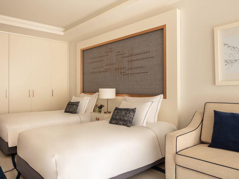 Hotelzimmer mit zwei großen Betten, cremefarbenen Wänden und hellen Möbeln, hell und einladend.