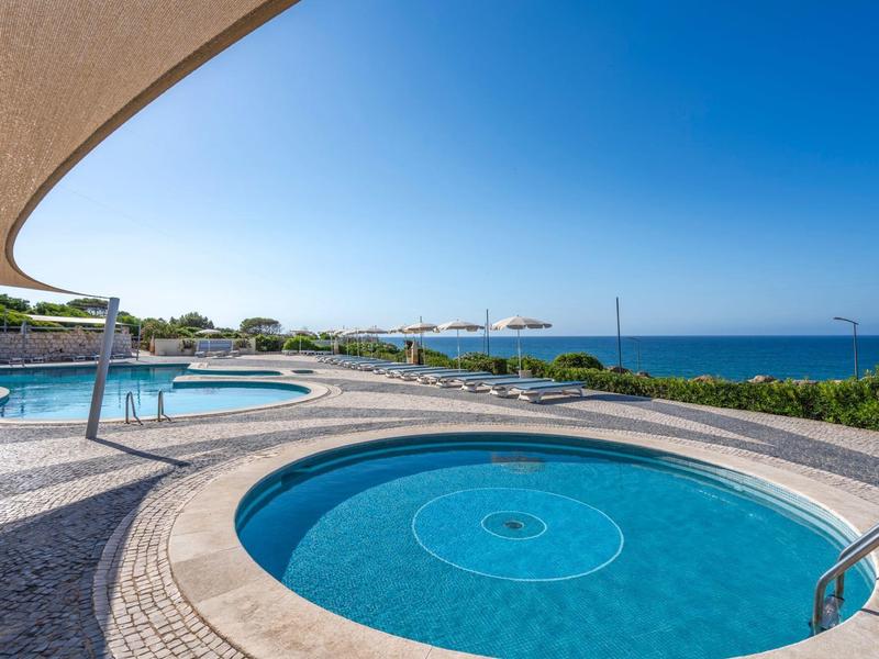 Runder Pool im Vordergrund, rechteckiger Pool dahinter, blauer Himmel und Meer im Hintergrund.