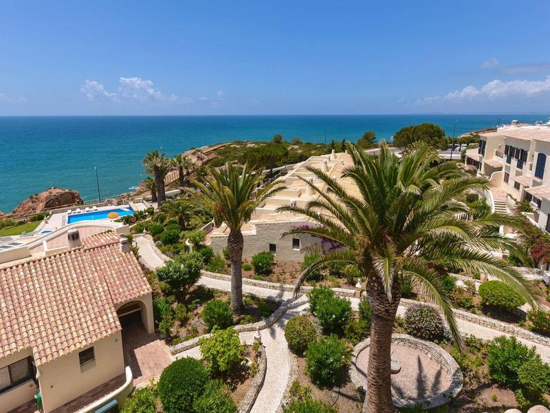 Blick auf Küstenlandschaft mit Palmen, Gebäuden, Gartenanlagen und weiter Blick aufs blaue Meer.