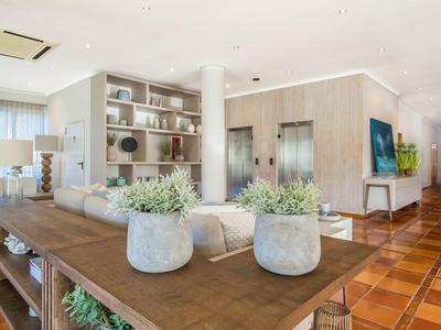 Helles Wohnzimmer mit Holzboden, weißen Möbeln, Pflanzen und eingebauten Regalen.