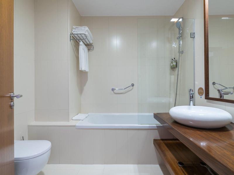 Baño moderno y luminoso con bañera, lavabo sobre encimera de madera y sanitario.