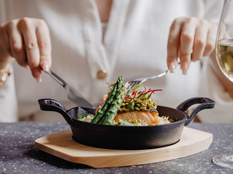 Persona con cubiertos lista para disfrutar un plato en sartén con verduras.