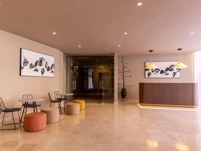 Área moderna del vestíbulo del hotel con asientos, recepción y diseño minimalista.
