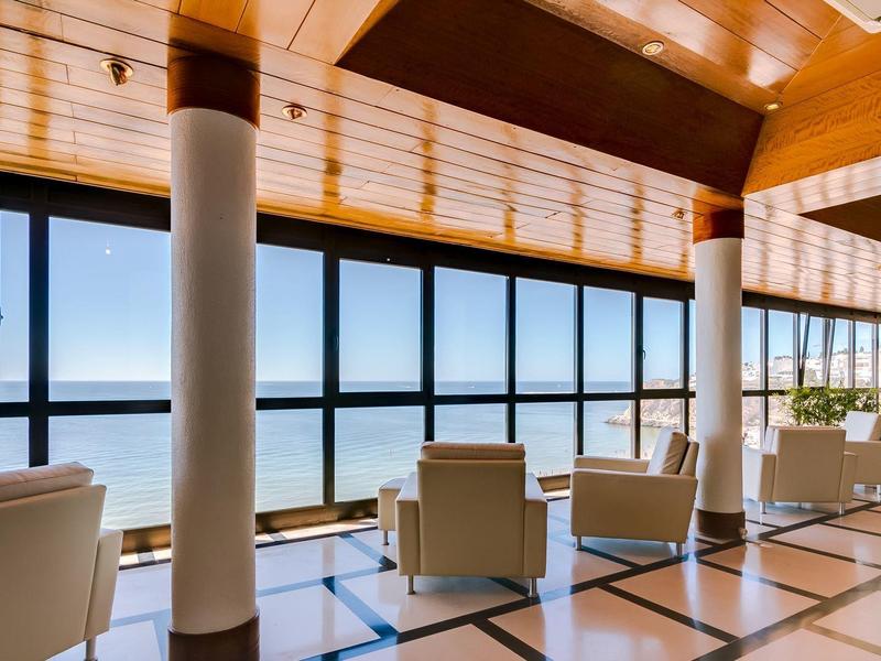 Nowoczesny hotelowy salon z dużymi oknami i widokiem na morze.