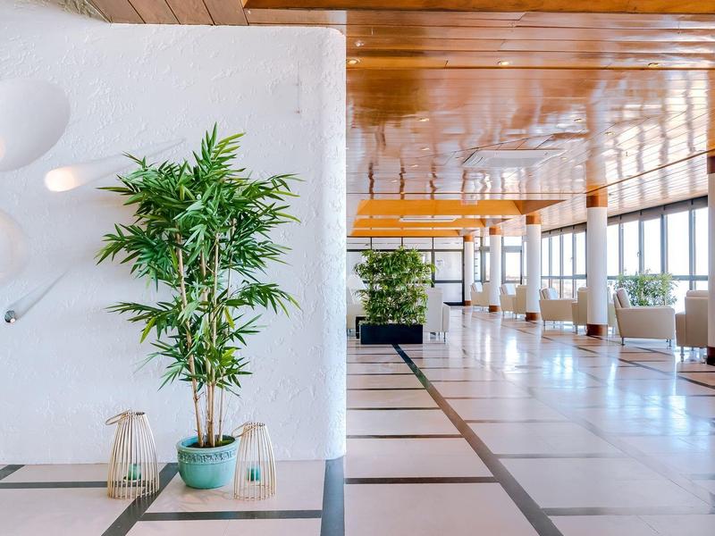 Jasna, nowoczesna przestrzeń lobby hotelowego z roślinami i dużymi oknami.