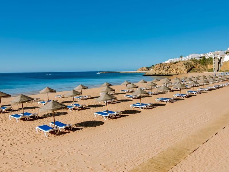 Plaża z rzędami leżaków i parasoli pod niebieskim niebem i morzem