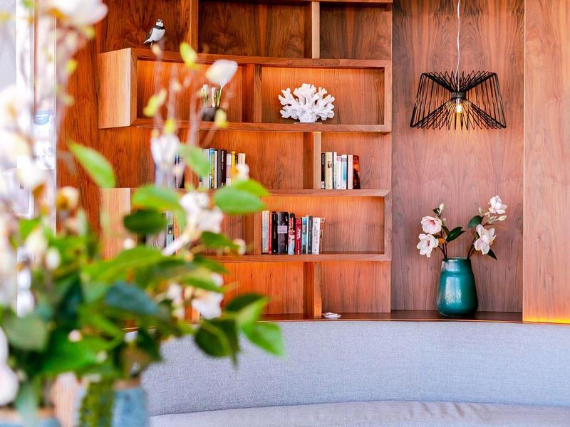 Nowoczesny hotelowy salon z drewnianymi półkami, dekoracjami i świeżymi kwiatami na pierwszym planie.