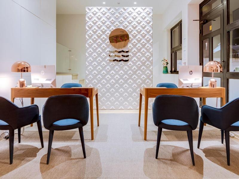 Nowoczesna jadalnia z białymi ścianami, drewnianymi stołami i niebieskimi krzesłami w hotelu.