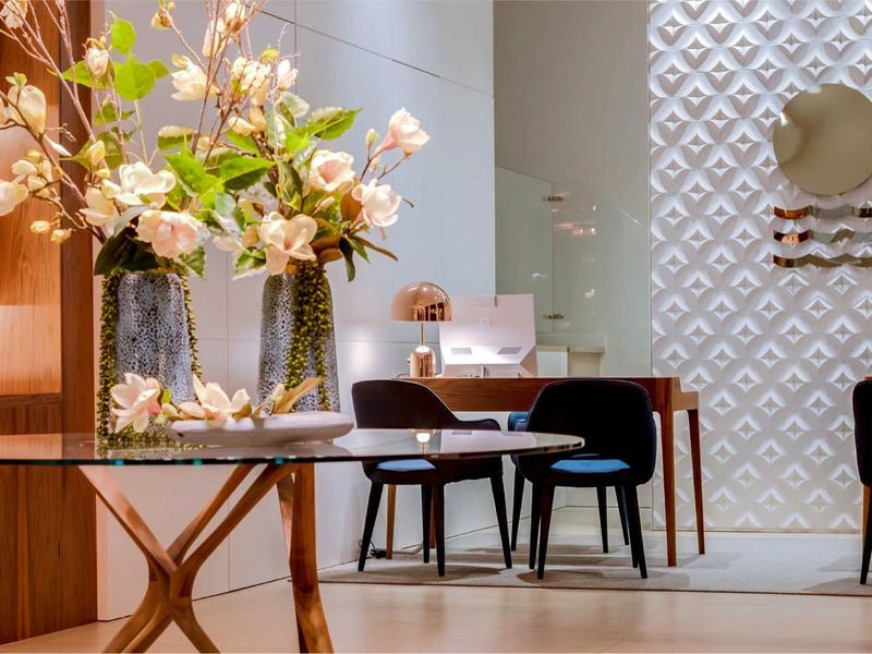 Nowoczesna przestrzeń lounge w hotelu z kwiatową dekoracją na okrągłym stole i krzesłami przy biurku.