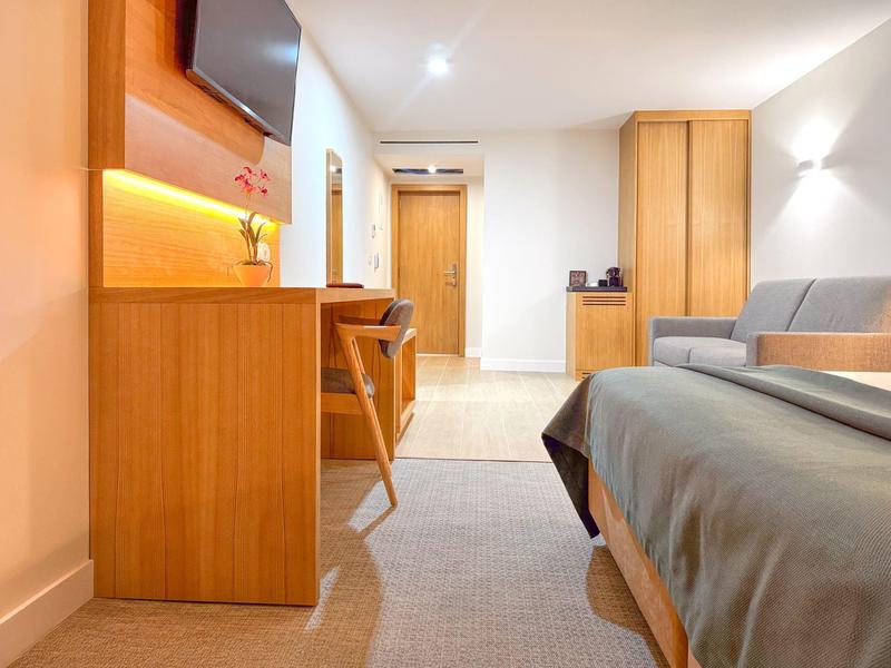 Nowoczesny pokój hotelowy z biurkiem, krzesłem, łóżkiem i telewizorem.