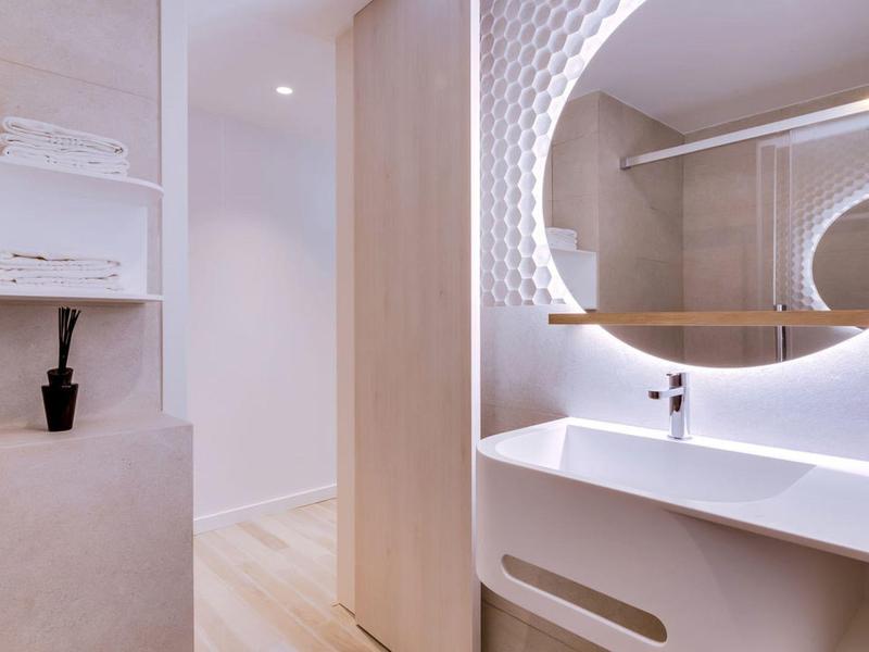 Nowoczesna łazienka z okrągłym lustrem i minimalistyczną umywalką w jasnym designie.