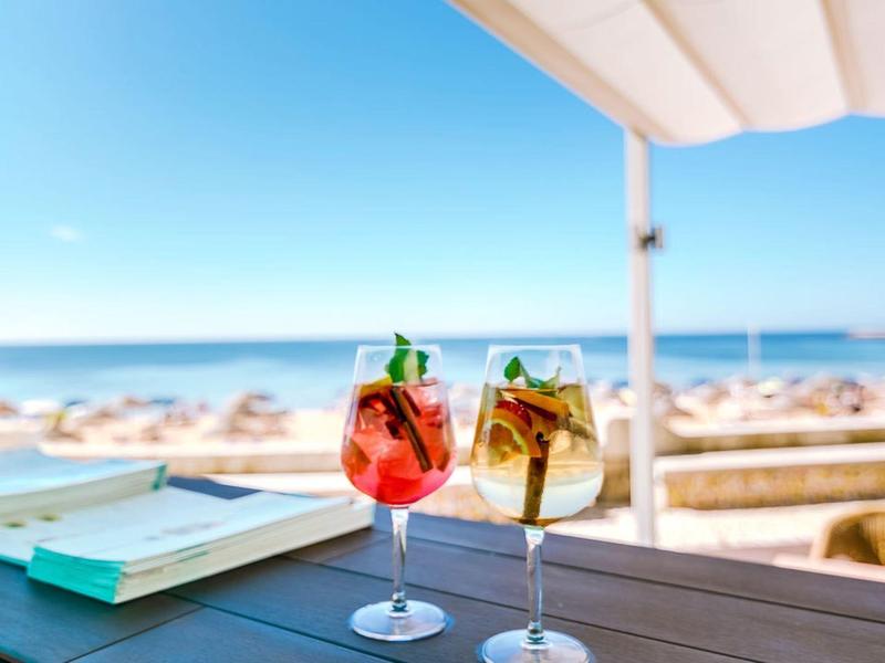 Dwa orzeźwiające koktajle na stole z widokiem na plażę i morze pod niebieskim niebem.