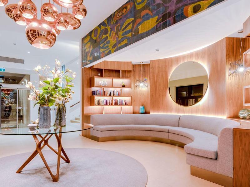 Nowoczesna lobby hotelowa z zakrzywionymi siedziskami i ciepłym drewnianym wykończeniem.