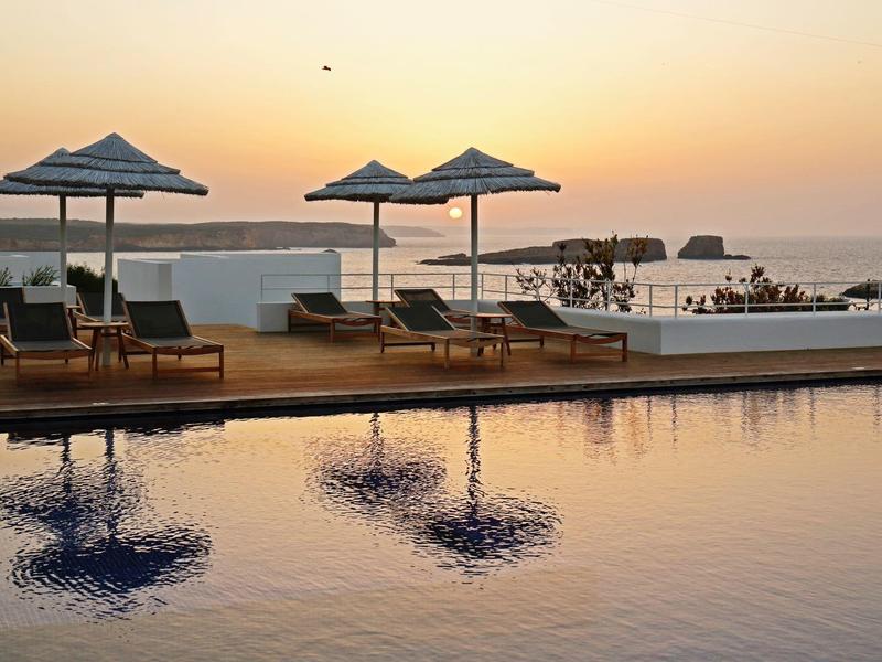 Bazénová oblast s lehátky a slunečníky při západu slunce u moře