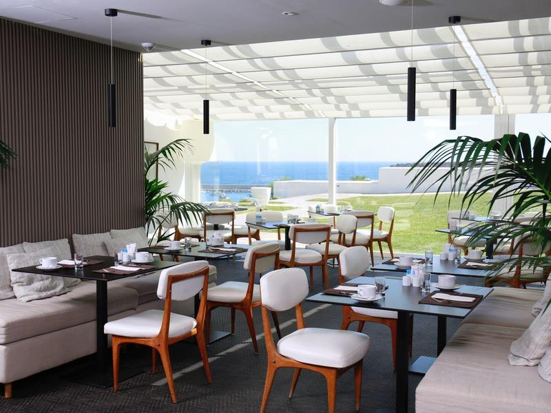 Moderní restaurace s výhledem na moře a elegantním dřevěným nábytkem.