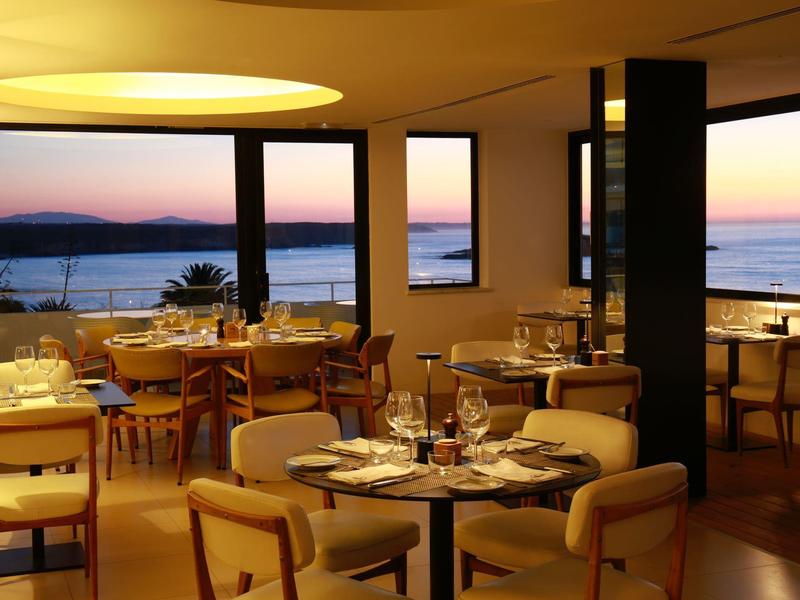 Elegantní restaurace s výhledem na moře při západu slunce.