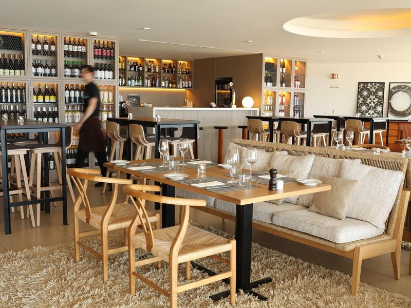 Moderní jídelní prostor s dřevěným nábytkem a regály na lahve vína.