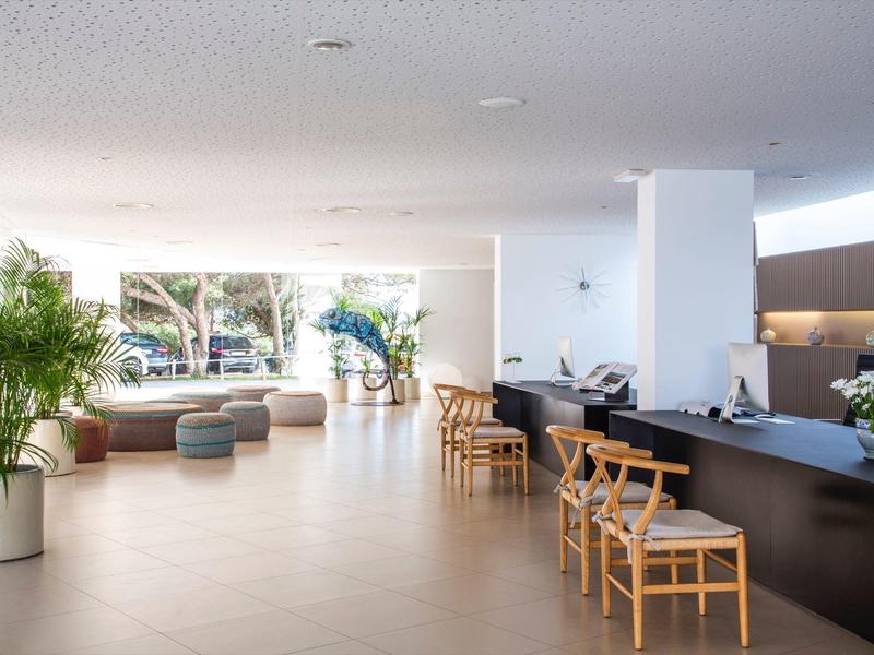 Světlá hotelová lobby s moderní sezením a pultem se židlemi.