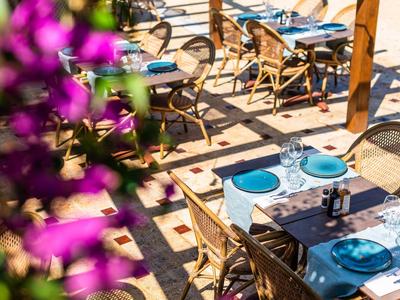 Terrasse eines Restaurants mit gedeckten Tischen und Stühlen in sonniger Atmosphäre